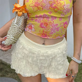 Person wearing a floral top and white lace shorts holding a pearl-handled clutch.